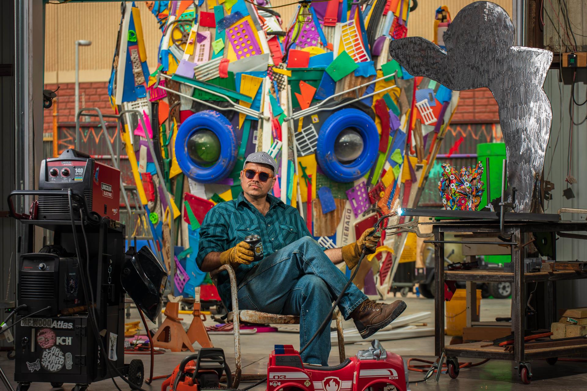 artist Gabriel Friedman sitting in chair holding welding tools