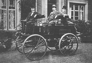 An electric vehicle built in 1884 with three people sitting in it