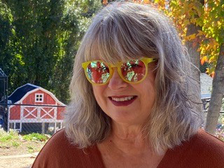 artist janice yeary wearing sunglasses with red barn in the background